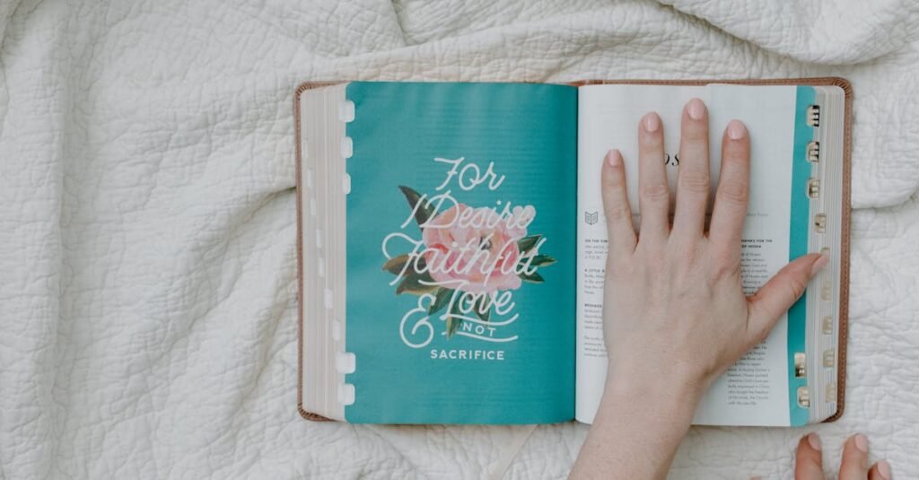 An open Bible on a white quilt with a hand resting on the page, promoting faith and reflection.