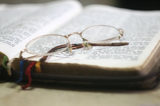 Close-up of eyeglasses atop an open Bible with colorful bookmarks, ideal for religious study themes.