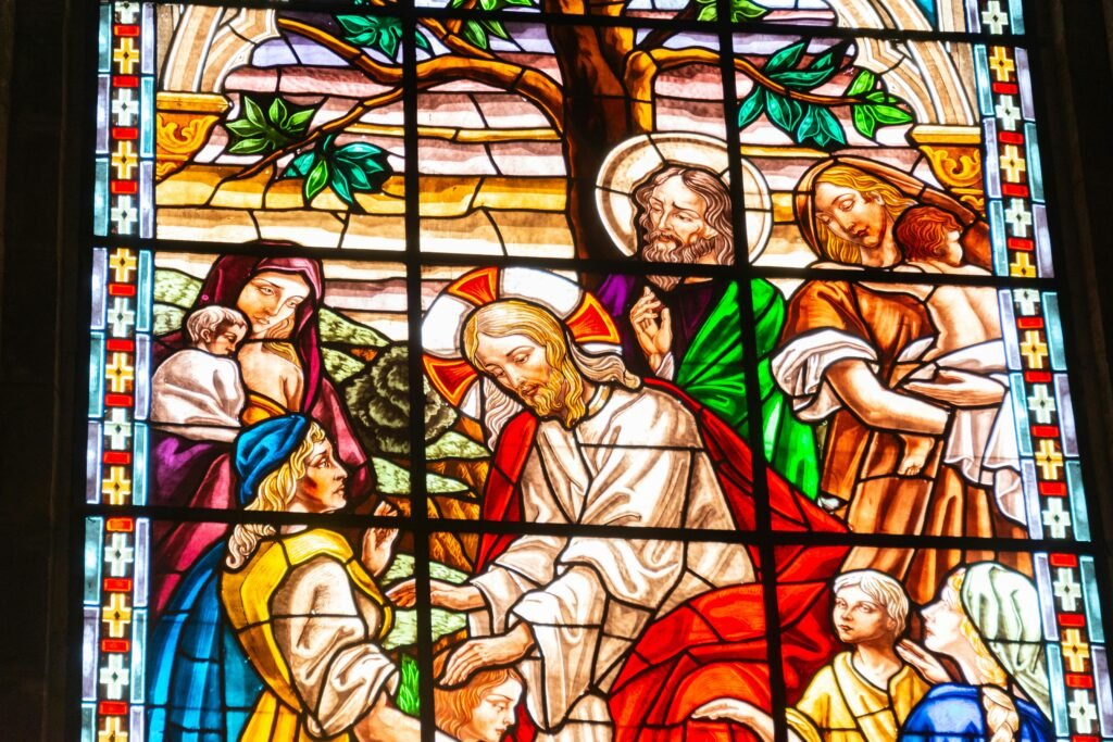 Colorful stained glass window illustrating a religious scene with vibrant characters and intricate designs.