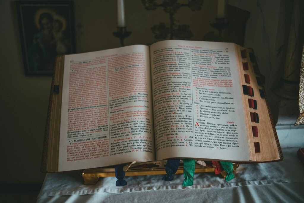 A Bible open on an altar with Latin text, featuring colored ribbons.