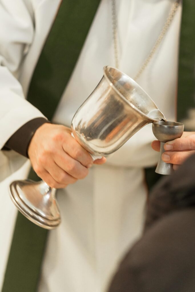 Close-up of priest pouring wine into a chalice during a holy communion ceremony.